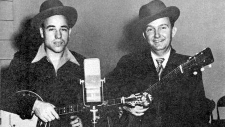 Earl Scruggs und Lester Flatt mit Banjo und Gitarre vor einem Mikrofon.