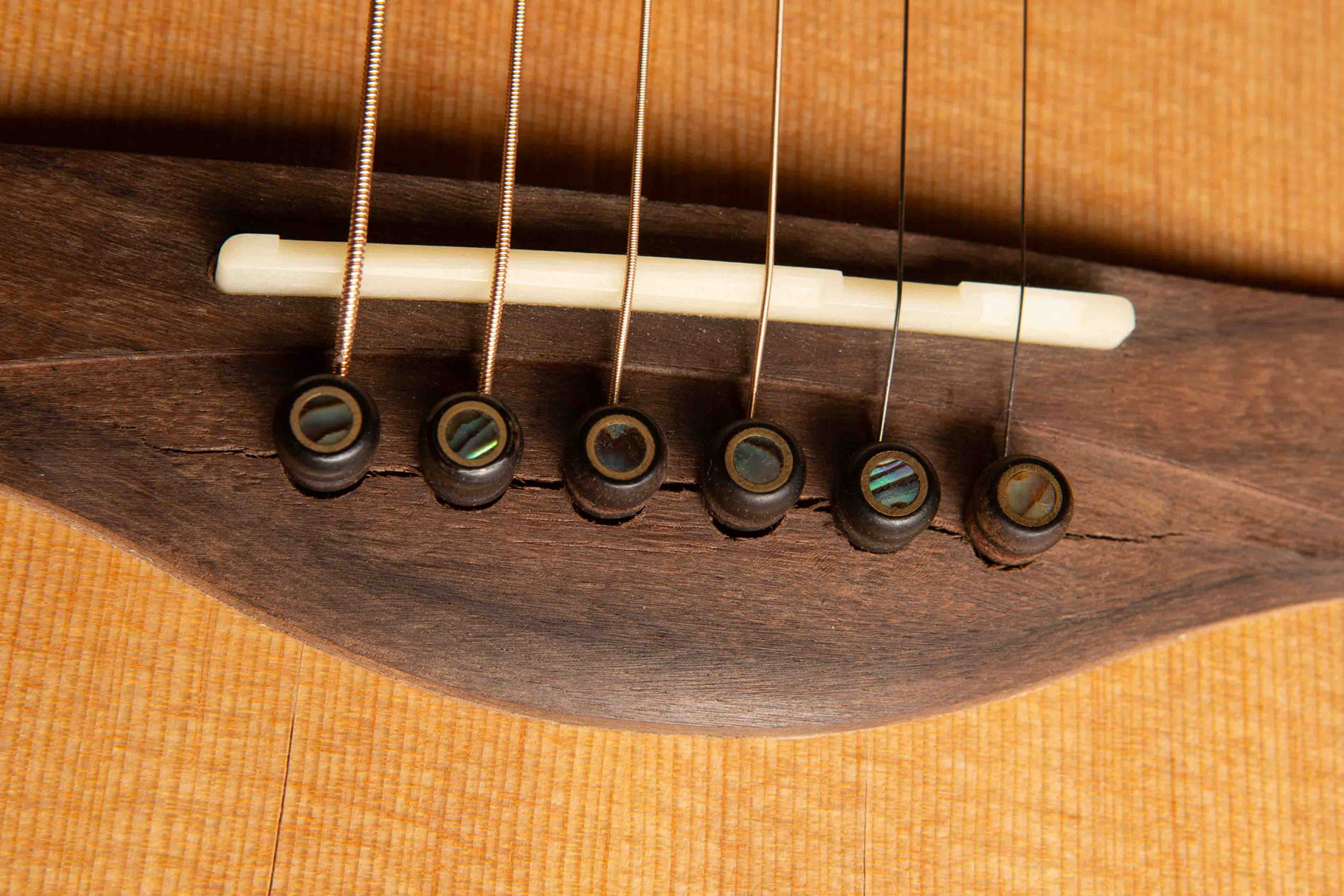 Bild eines gerissenen Gitarrenstegs aufgrund zu niedriger Luftfeuchtigkeit.