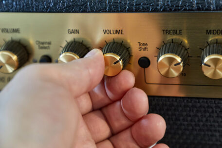 Volume-Regler eines Gitarrenverstärkers, der von Hand bedient wird.