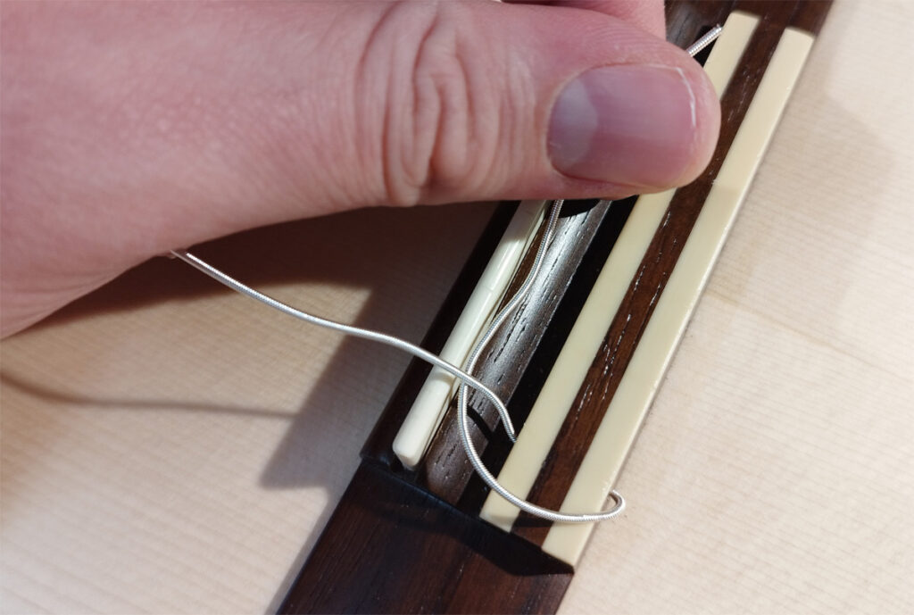 Schritt 3 zum Binden eines einfachen Knotens am Gitarrensteg.