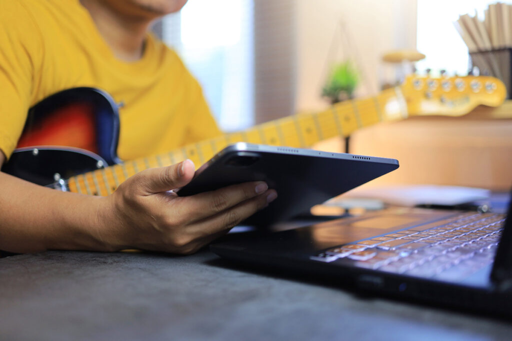 E-Gitarrist mit Laptop und Tablet.
