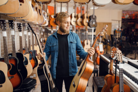 Mann beim Kauf einer Akustikgitarre